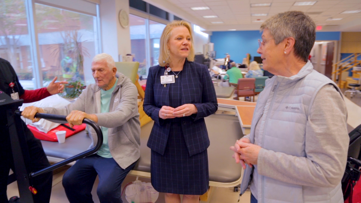 Beth Villena stands in the middle of the frame and speaks to a family member of a patient.