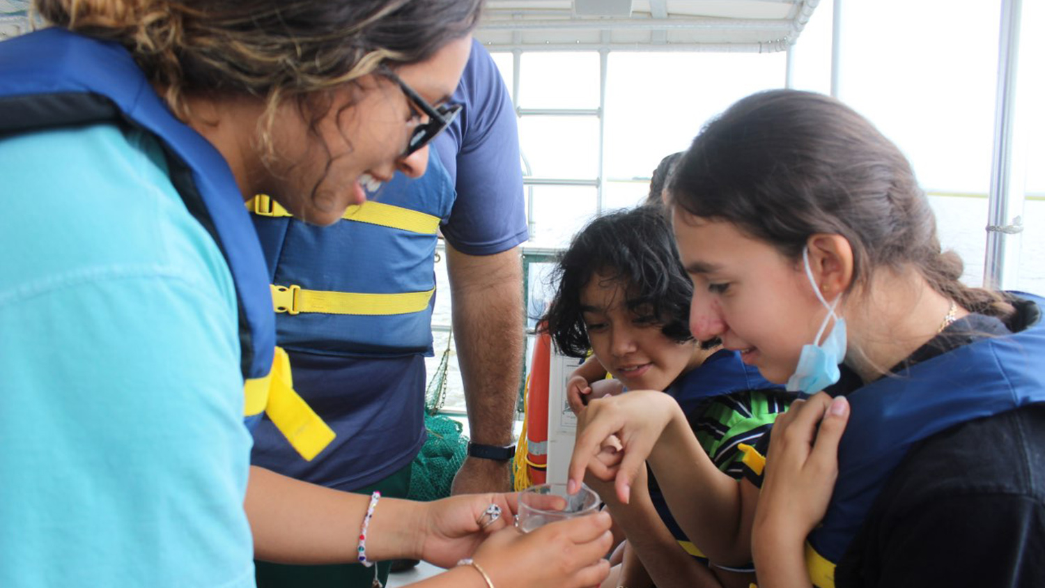 student shows young girls wildlife in cup